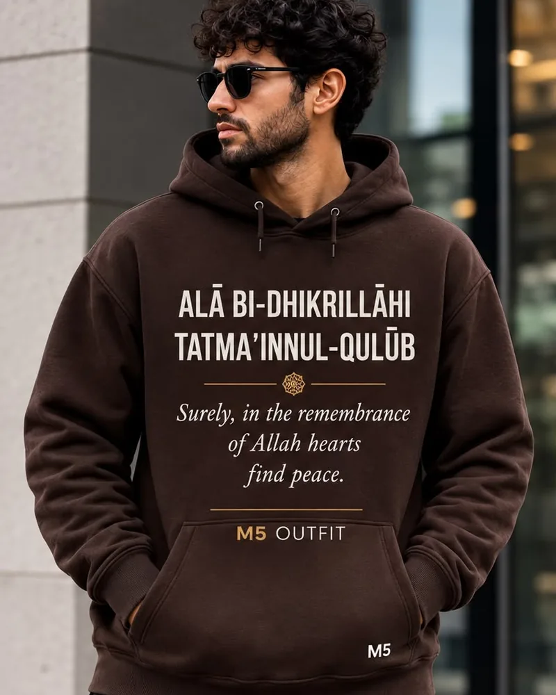 Model wearing a brown M5 Outfit hoodie printed with the Arabic and English phrase Ala Bi-Dhikrillahi Tatma'innul-Qulub