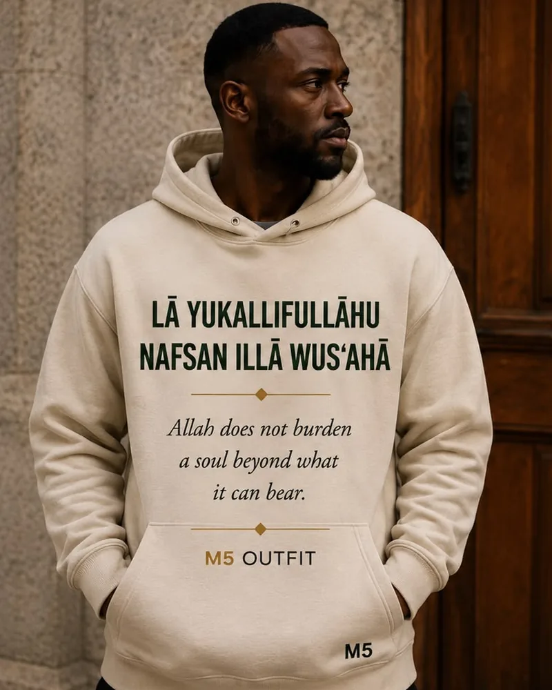 Model wearing a sand M5 Outfit hoodie printed with the Arabic and English phrase La Yukallifullahu Nafsan Illa Wus'aha