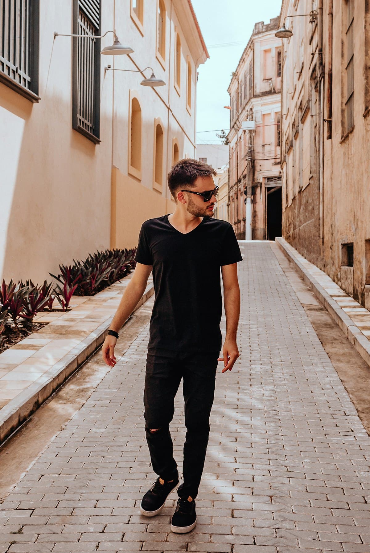 Model in an all-black M5 Outfit fit walking a European street